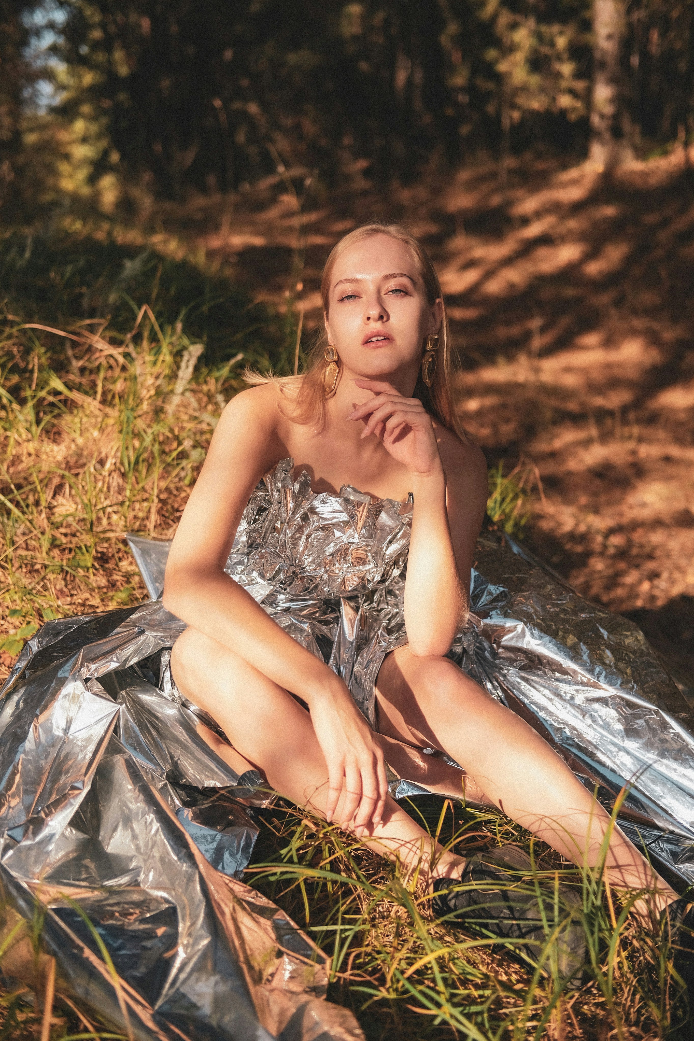 woman in white and black floral spaghetti strap dress sitting on green grass field